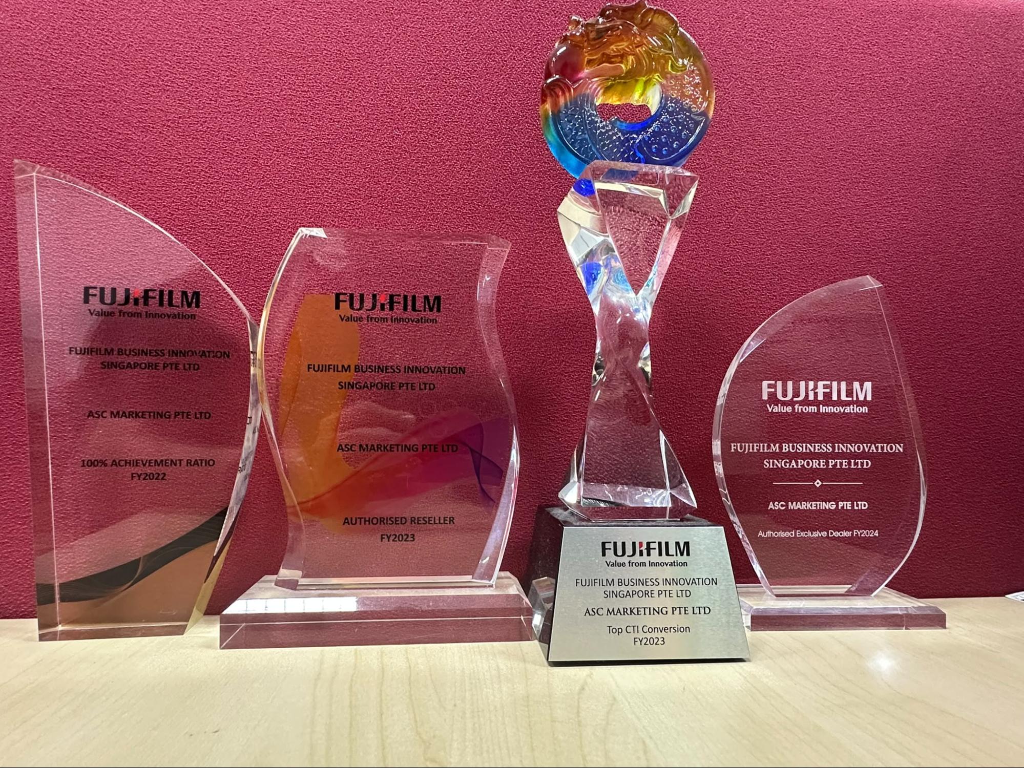 ASC Marketing's four Fujifilm Business Innovation Singapore awards displayed together: 100% Achievement Ratio FY2022, Authorised Reseller FY2023, Top CTI Conversion FY2023, and Authorised Exclusive Dealer FY2024